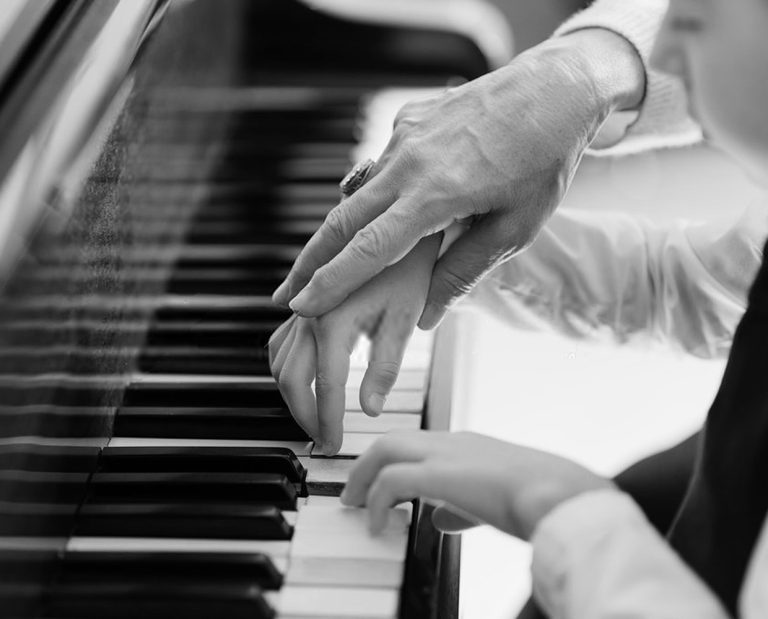 hand of an experienced pianist, music teacher helping young students